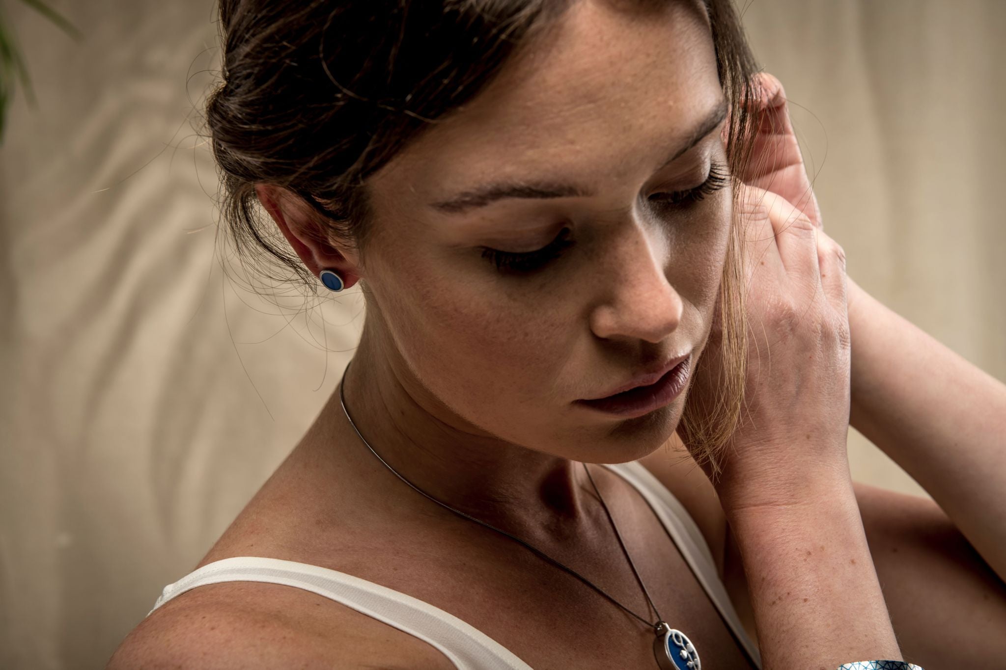 Model wearing matching blue earrings and necklace.