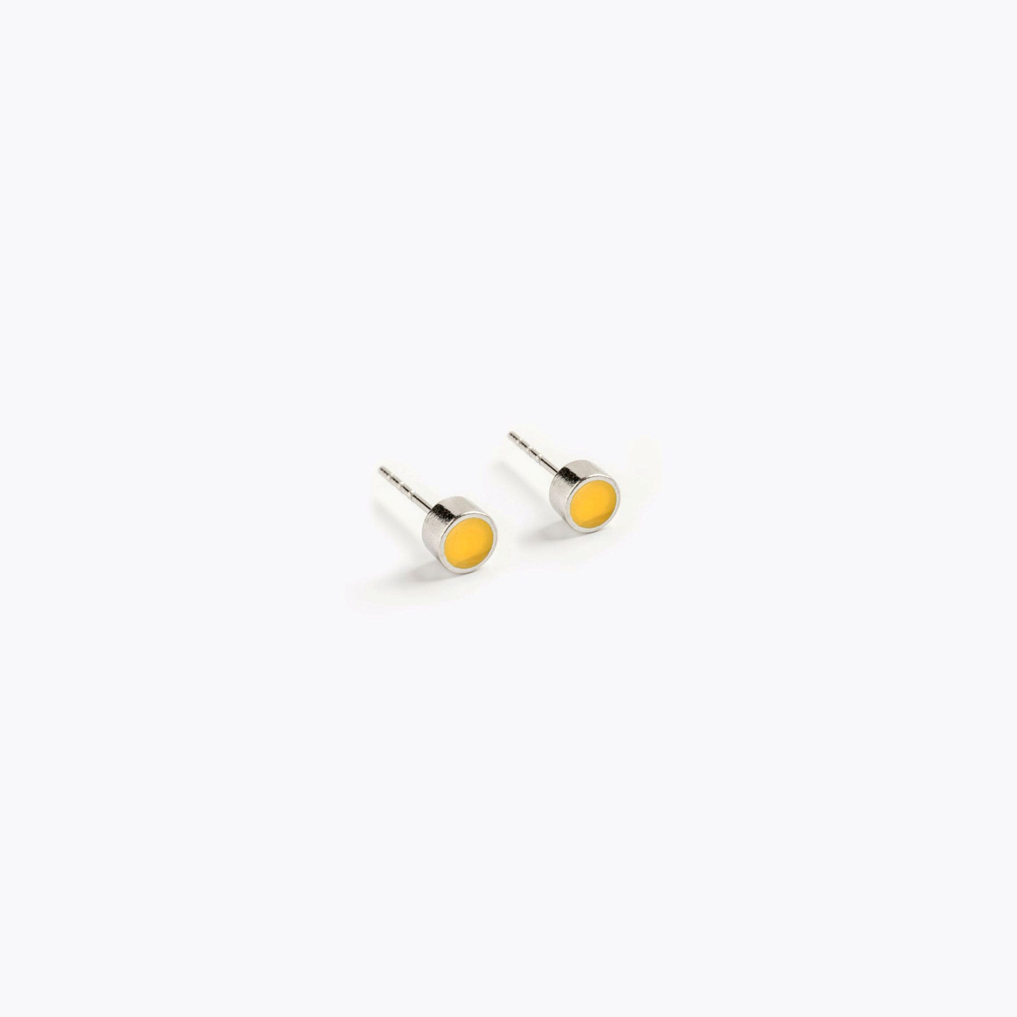 A simple pair of small, yellow, circular stud earrings.