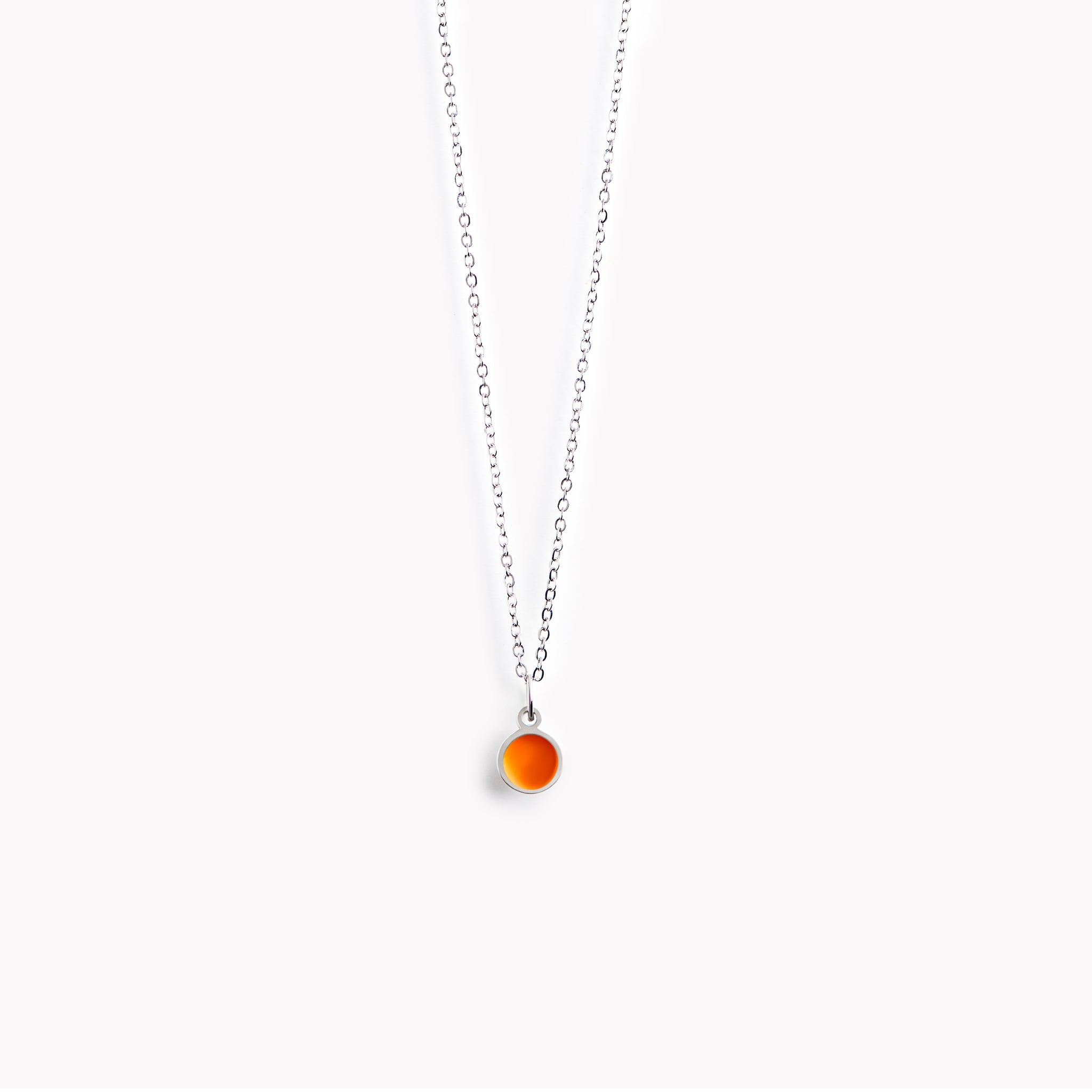 A simple, delicate, circular necklace with a bright orange centre and a polished pewter surround.