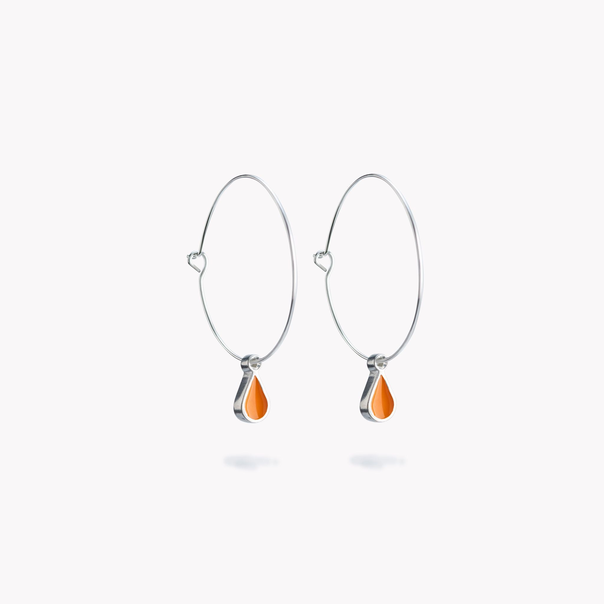 A simple pair of hoop earrings with orange hanging droplets.