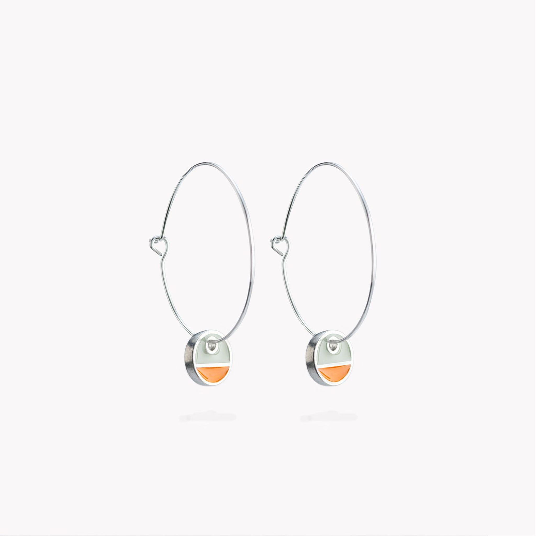 A simple pair of hoop earrings with orange and grey circular hanging discs.