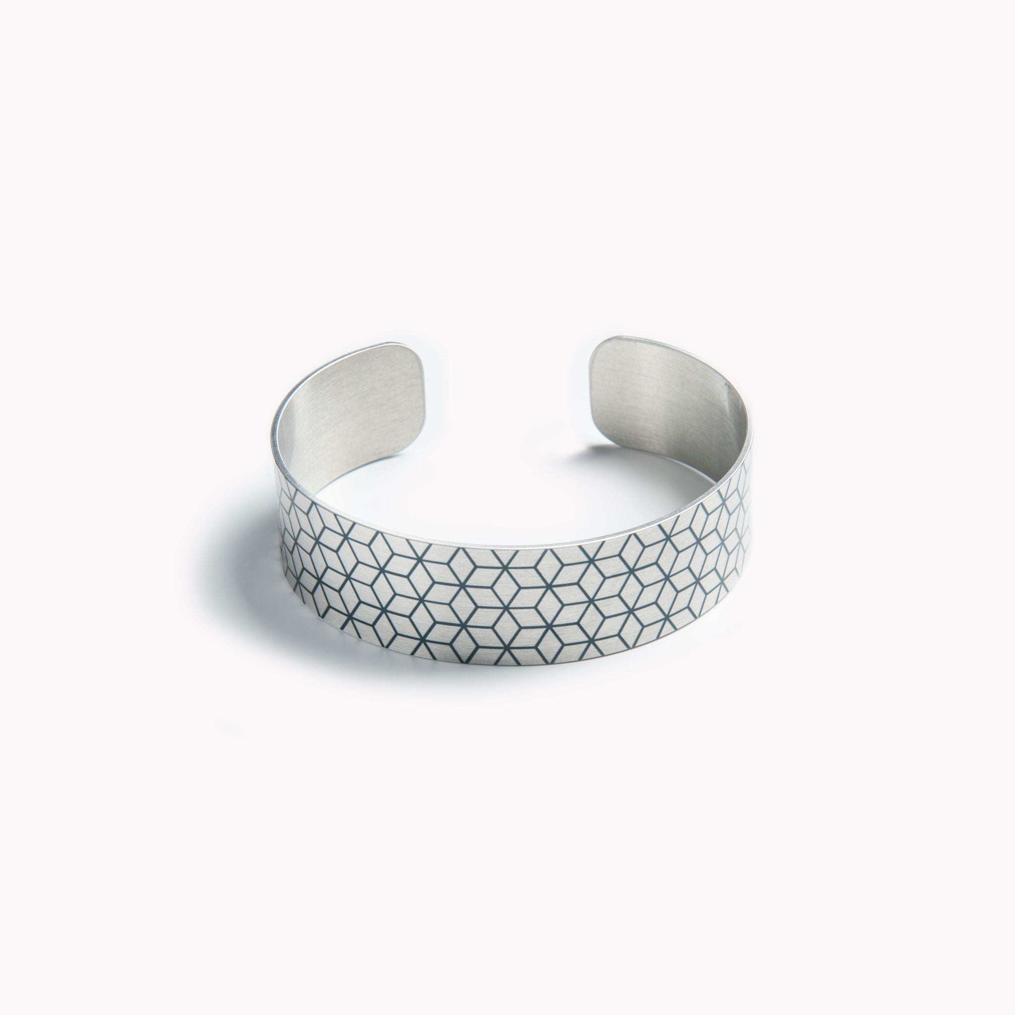An intricately detailed cuff bracelet with a black geometric pattern.