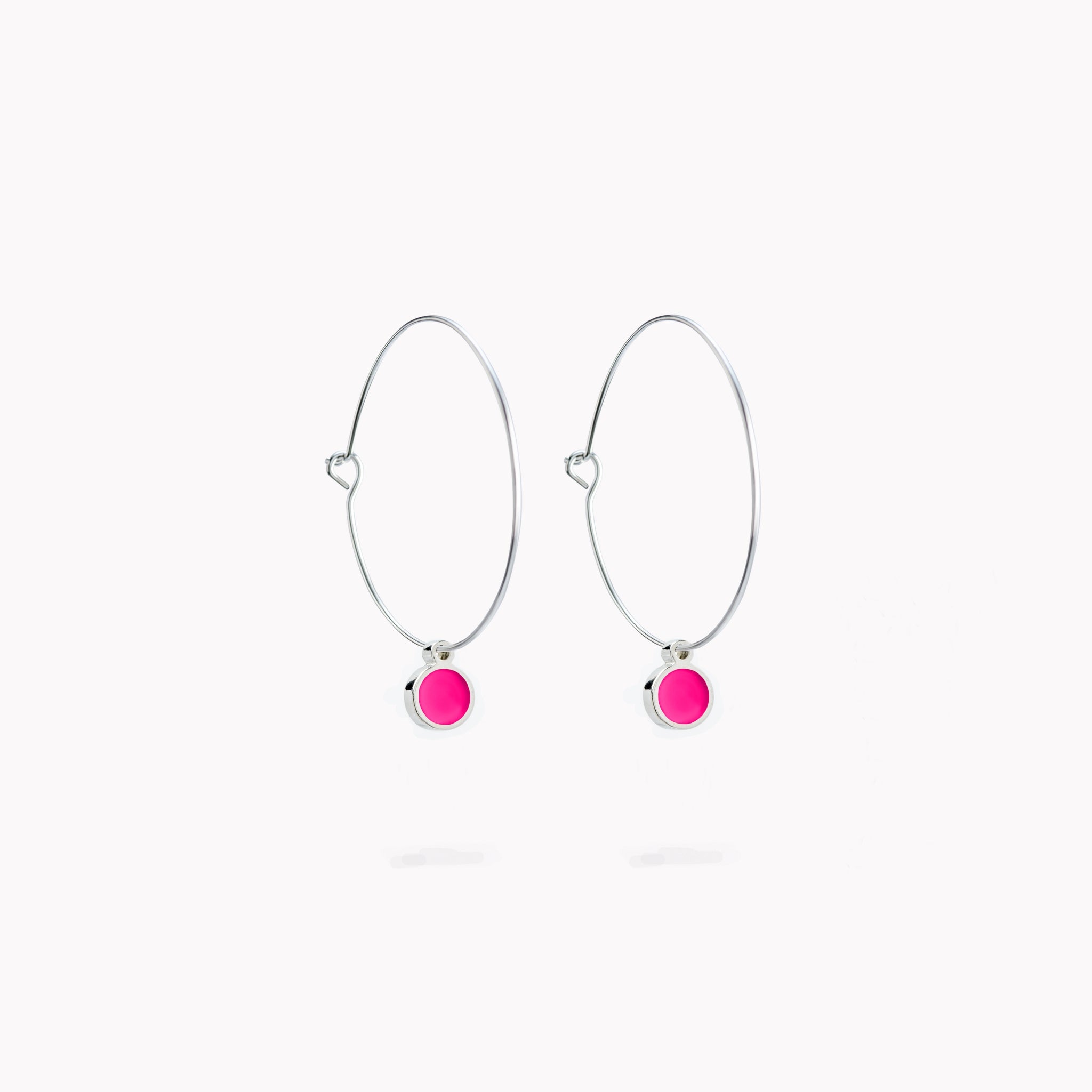 A pair of simple hoop earrings, each with a hot pink hanging circular form.