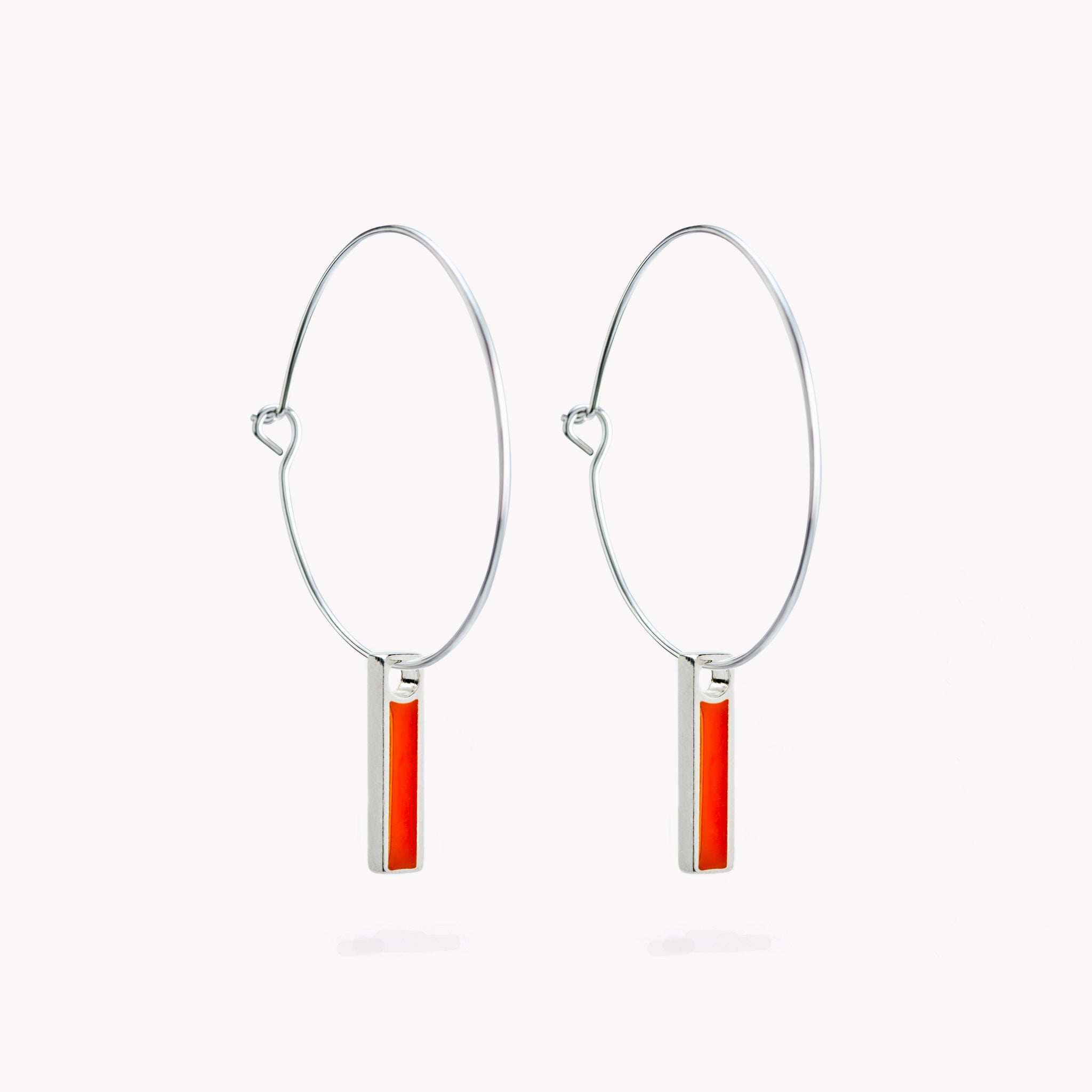 A pair of simple hoop earrings with a hanging orange bar.
