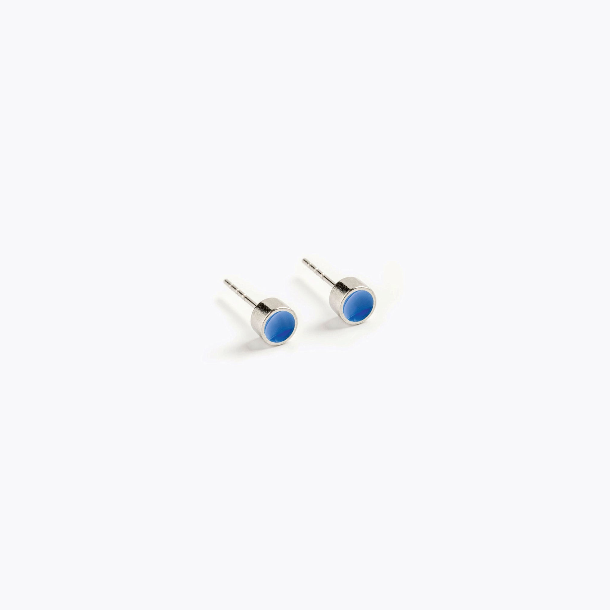 A simple pair of small, blue, circular stud earrings.