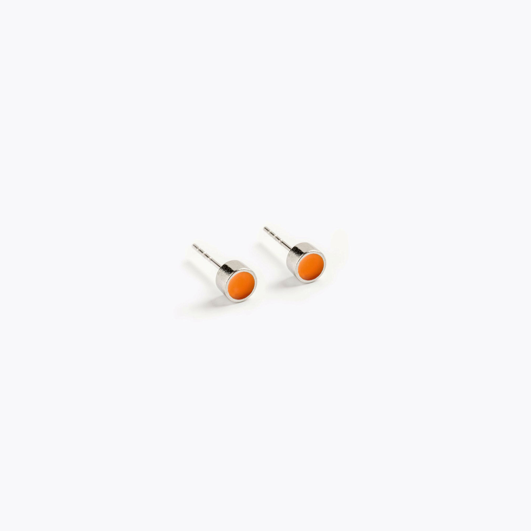 A simple pair of small, orange, circular stud earrings.