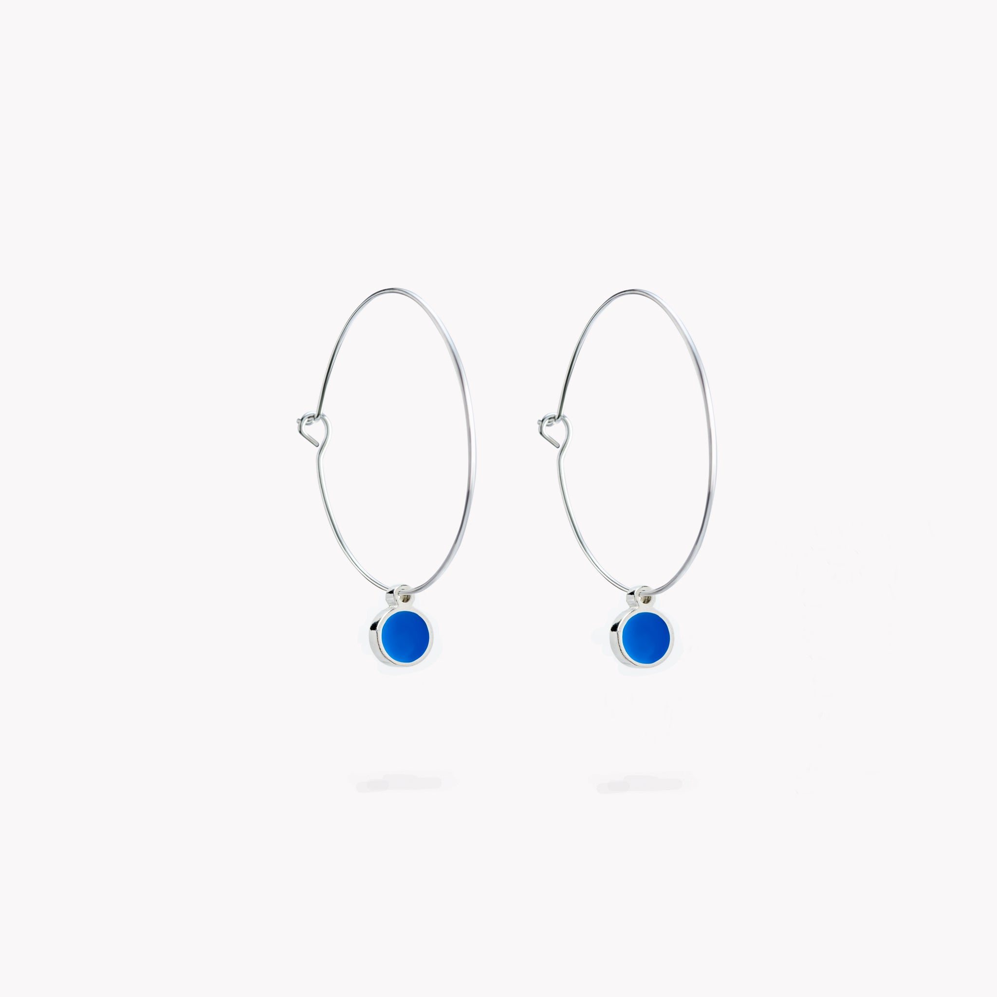 A pair of simple hoop earrings, each with a bright blue hanging circular form.