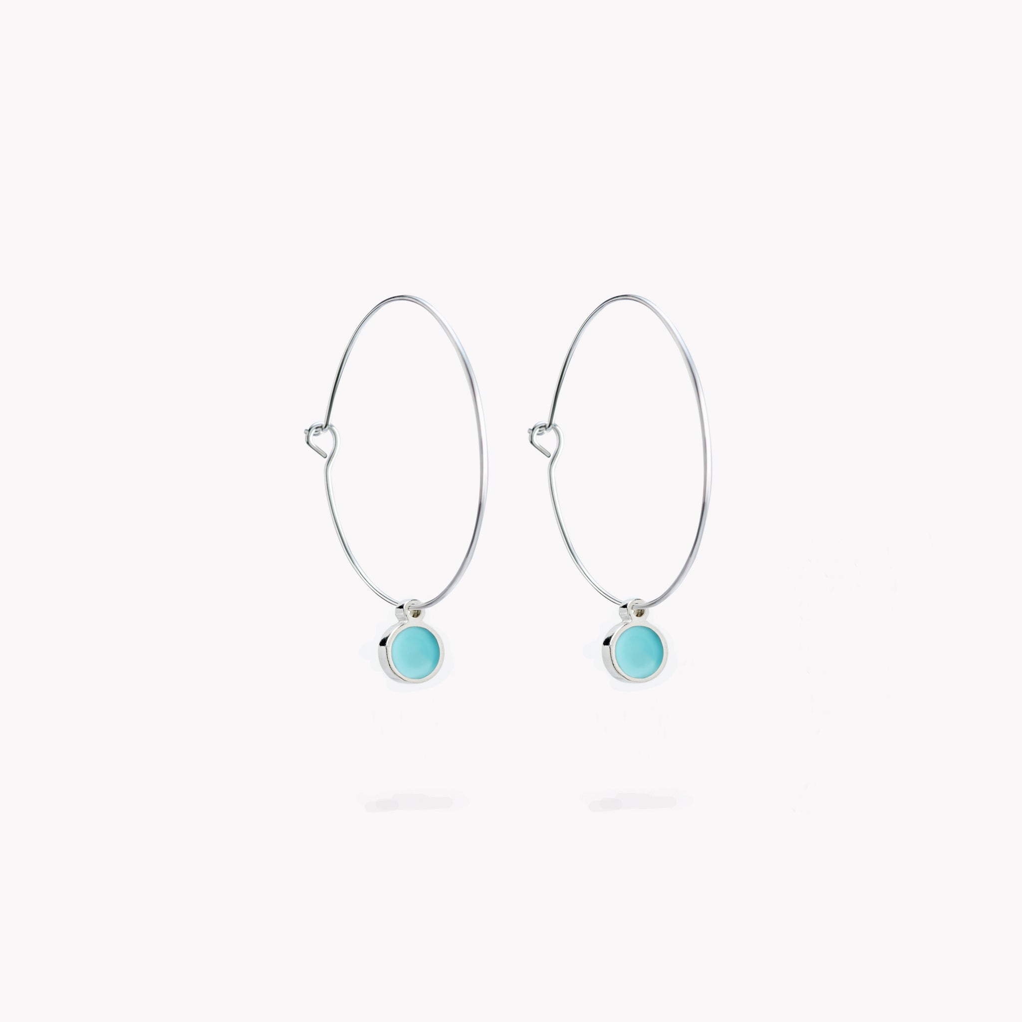 A pair of simple hoop earrings, each with a cool turquoise hanging circular form.