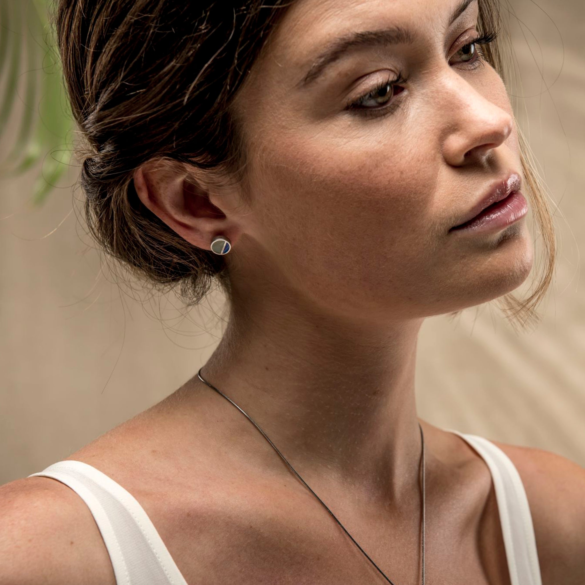 Fashion model wearing a simple, blue & grey, circular stud earring.