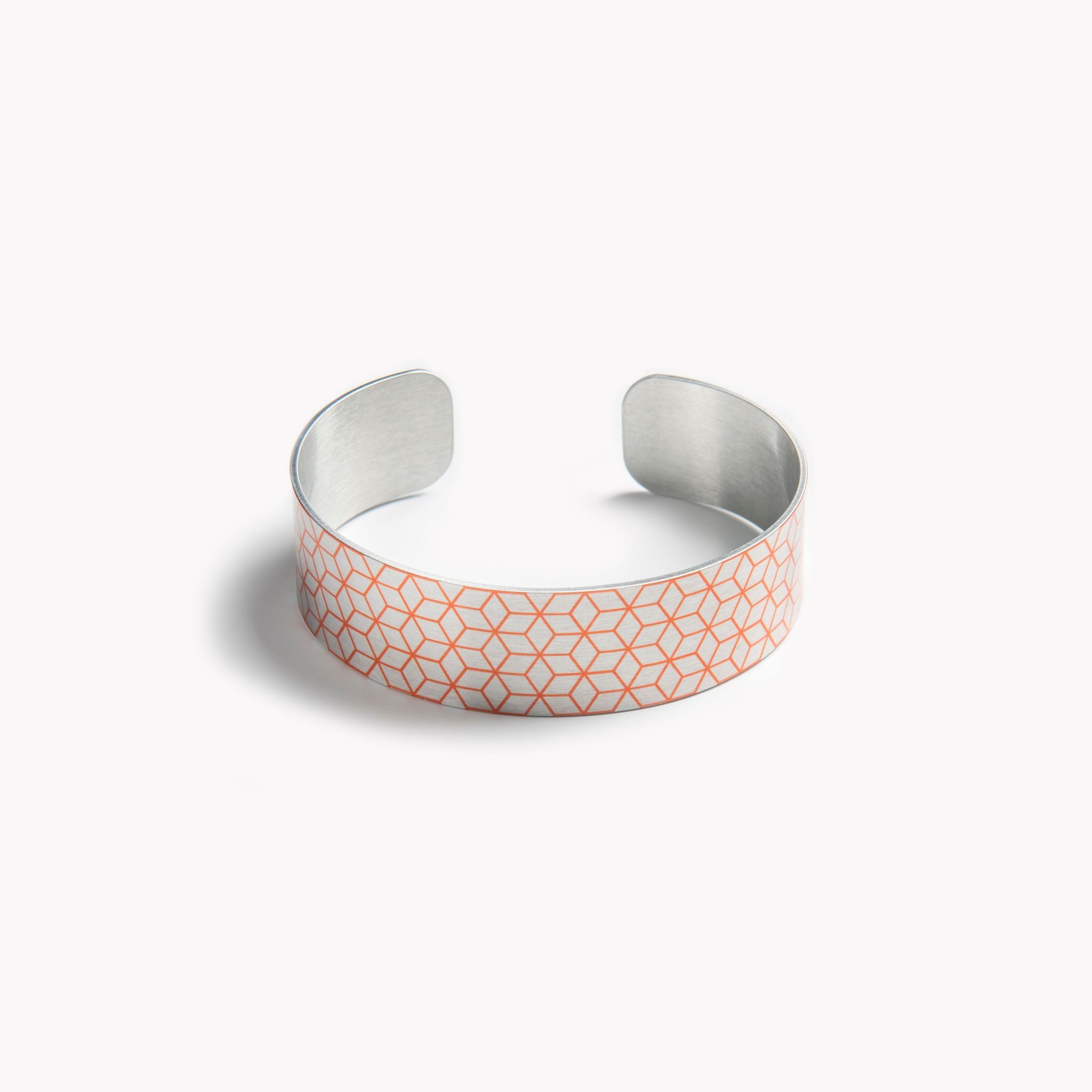 An intricately detailed cuff bracelet with an orange geometric pattern.