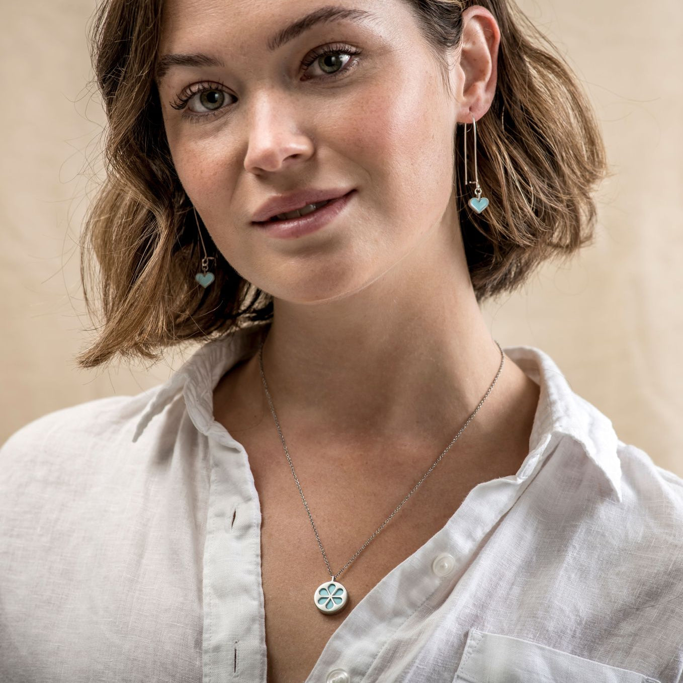 Fashion model wearing a simple, delicate, turquoise flower necklace.