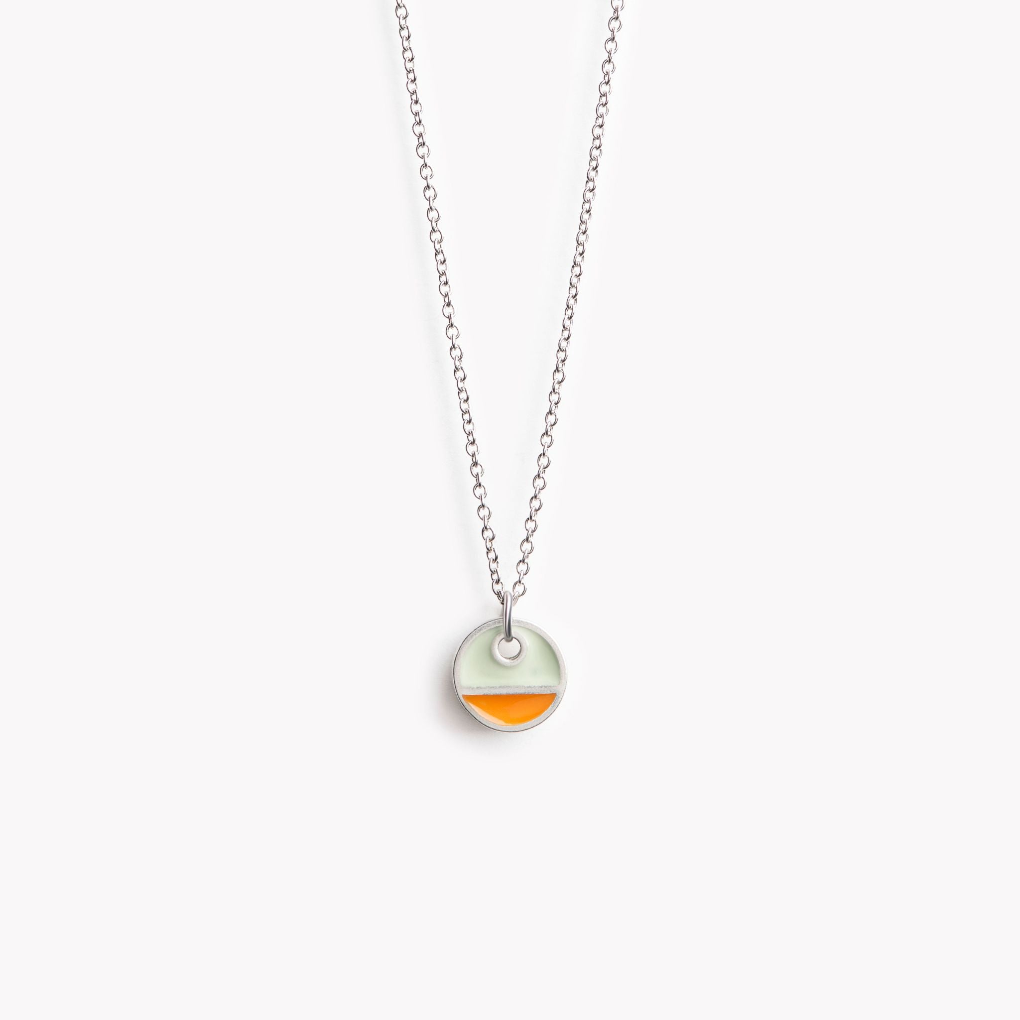 A simple circular pendant necklace with a horizontal division. In orange and grey.