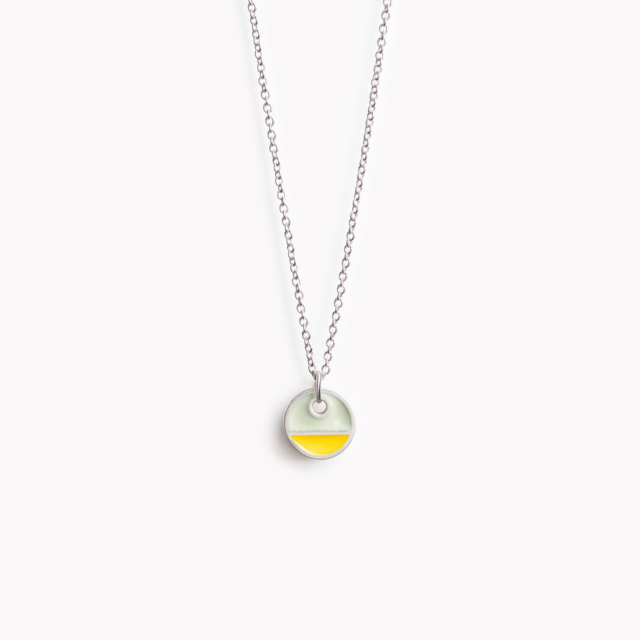 A simple circular pendant necklace with a horizontal division. In yellow and grey.