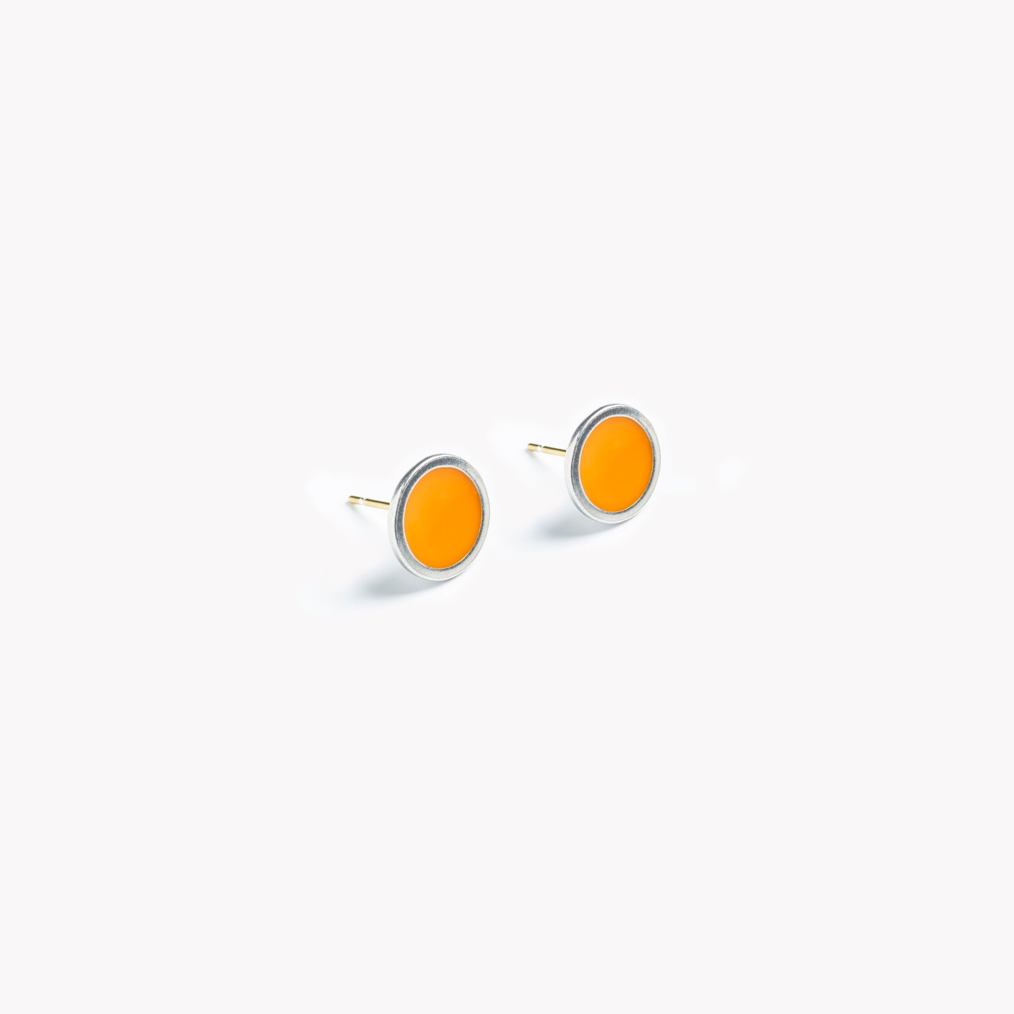 A simple pair of bright orange circular stud earrings.